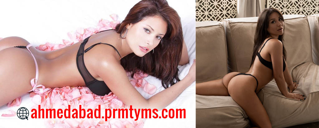 Two women in black lingerie posing indoors, one lying on a bed surrounded by rose petals and the other sitting on a sofa, with text 'ahmedabad.prmtyms.com' displayed.